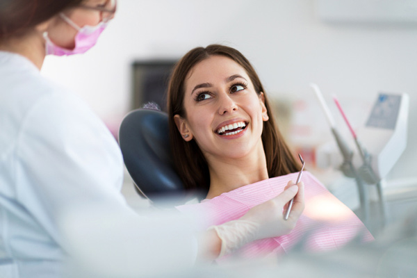 Woman smiling in a dental chair learning about the dental services at Martin Periodontics in Mason & North Cincinnati, OH.