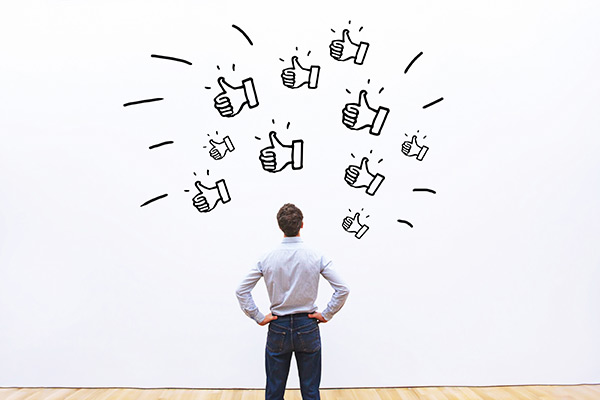 Man standing before a wall covered with illustrations of thumbs up 