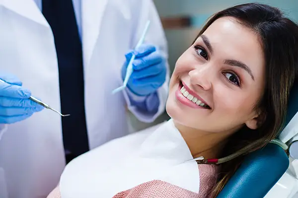Image of a woman smiling before a dental professional looks at her teeth.