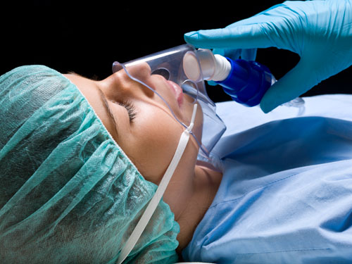 Gloved hand holding breathing mask to sleep patient's face