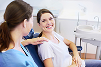 Smiling woman sitting in a chair, going over patient information with the dental profesional, at Martin Periodontics in Mason, OH.