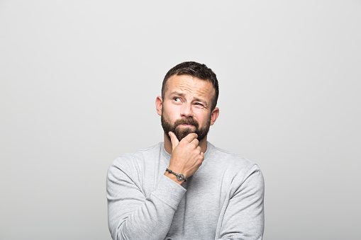 A man stroking his beard while thinking hard about dental implants at Martin Periodontics 