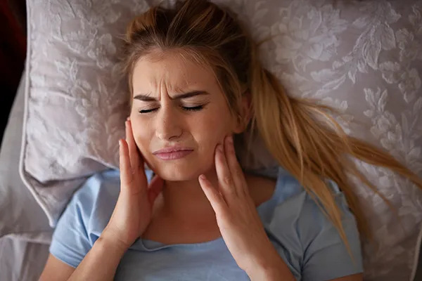 Woman lying in bed with bruxism before making an appointment at Martin Periodontics in Mason, OH